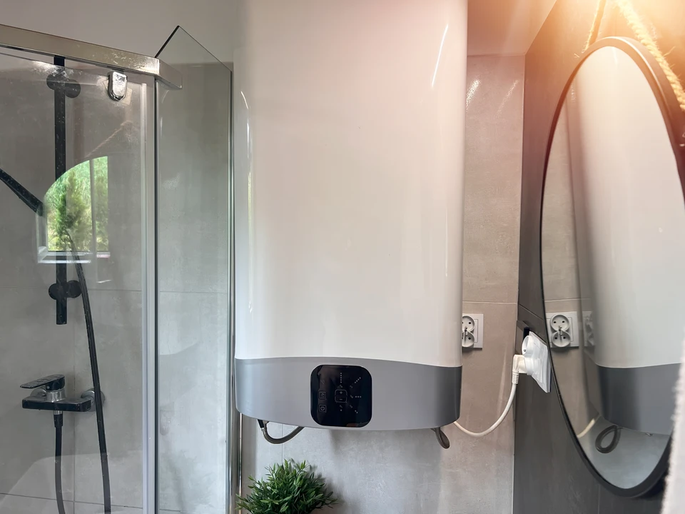 Intérieur de salle de bain moderne avec douche à l'italienne vitrée et chauffe-eau électrique mural en cours d'installation