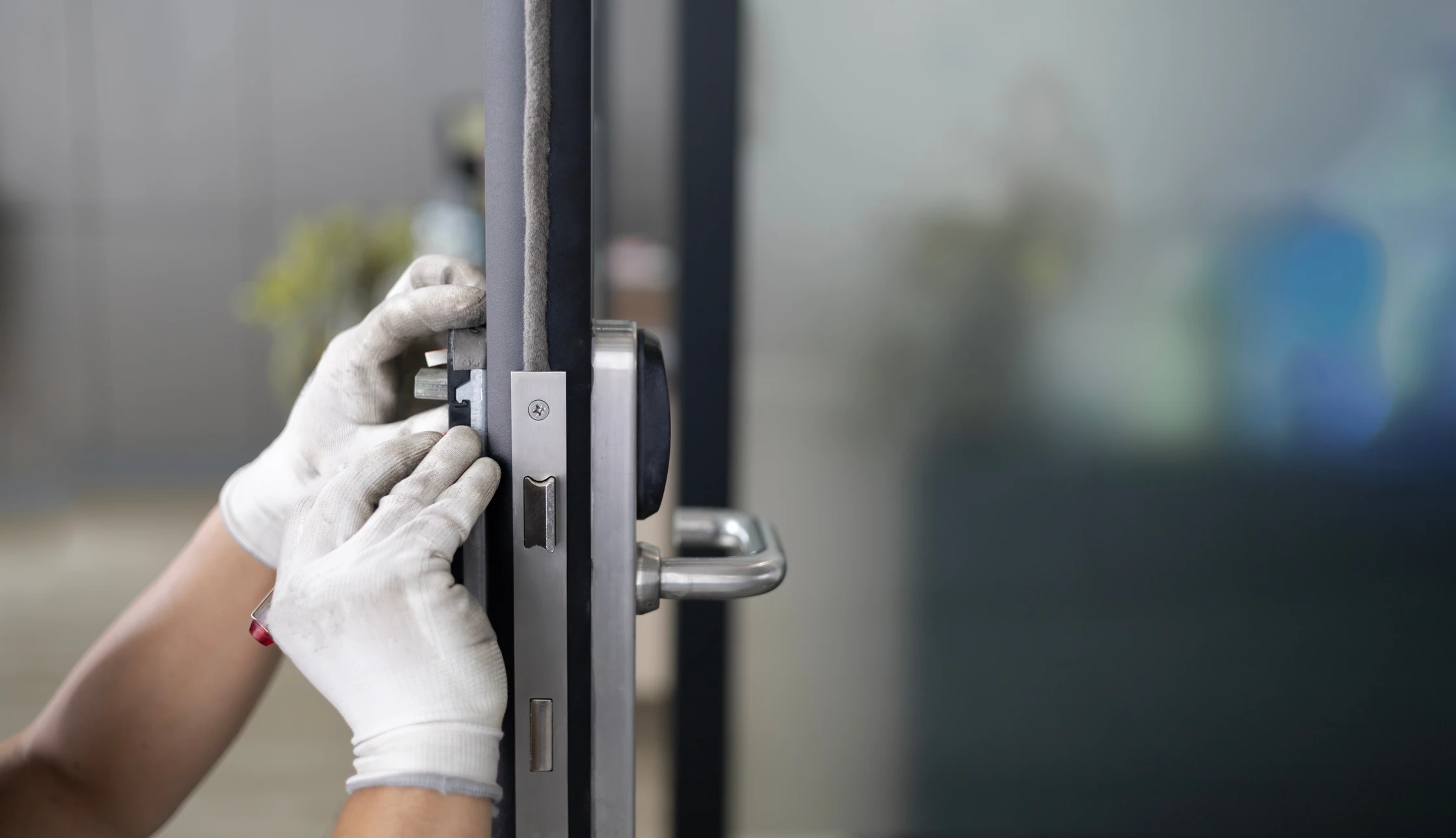 Int&eacute;rieur, mains d'un serrurier manipulant des outils de crochetage sur une serrure de porte